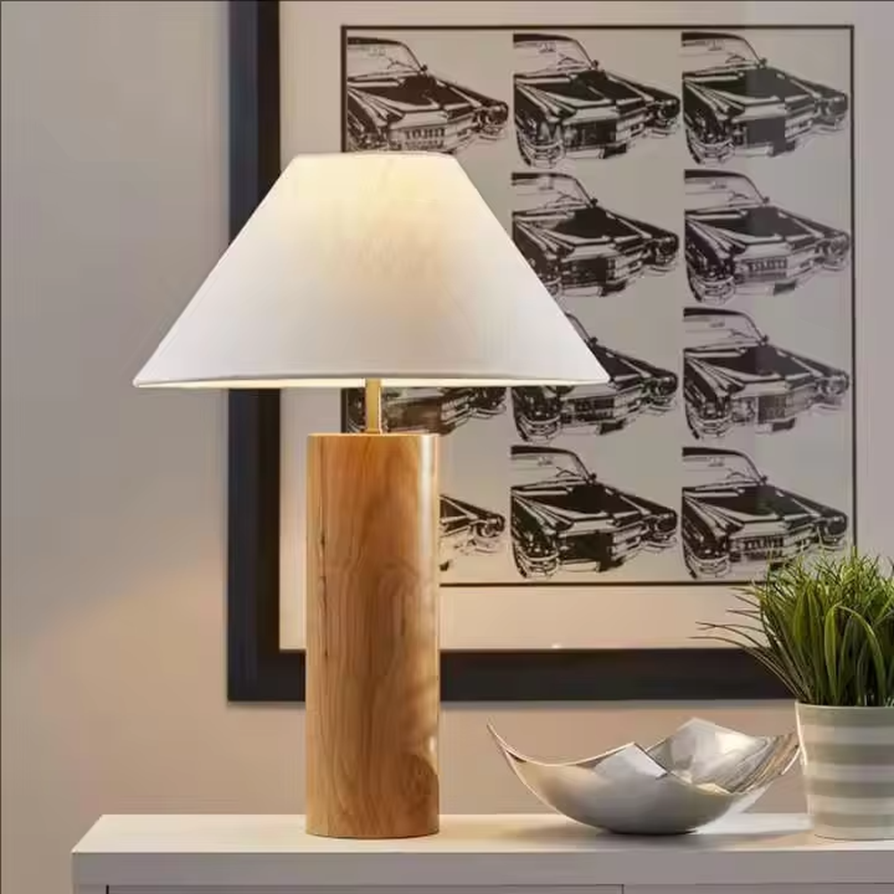 This is a natural minimalist wooden table lamp with a cylindrical solid wood base and a white fabric slant lampshade. It features a rustic and natural design with a warm ambiance. It is used for local desktop lighting and decoration, creating a natural and warm atmosphere. It is suitable for Nordic-style home bedrooms, Japanese art homestays, literary cafes and other places.