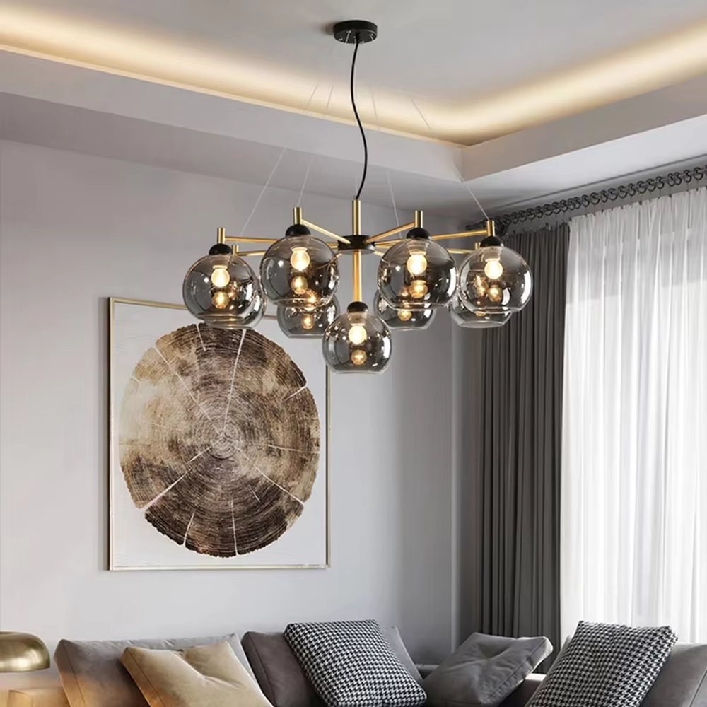 Modern light luxury black and gold branch chandelier, featuring a radial frame in black and gold metal paired with gradient smoky gray glass ball lampshades. Its sophisticated and layered design combines style and ambiance, making it a high-end decorative lighting fixture that elevates the space's aesthetic.