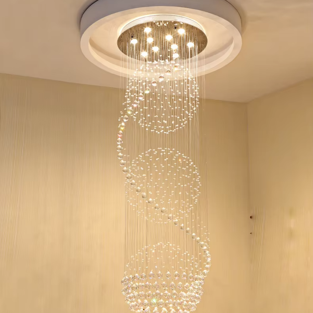 This European luxury spiral staircase crystal chandelier features a metal ceiling base, with dense crystal bead strings hanging down to form a dynamic spiral-rising shape. When lit, light refracts through the crystal to emit a brilliant and soft glow, combining a dynamic texture with an ambient atmosphere. Ideal for villa high-ceiling living rooms, hotel lobbies, duplex hollow spaces, and other areas, it adds an elegant and exquisite touch to European luxury or modern light luxury environments.