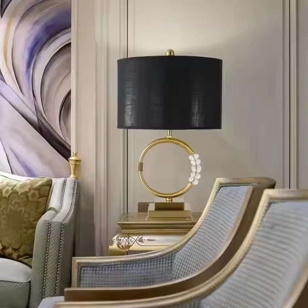 This is a luxurious retro-style table lamp with a golden circular base, a black fabric lampshade, and crystal elements, featuring an elegant and grand design. It is used for local desktop lighting and decoration, enhancing the luxurious retro ambiance of the space. It is suitable for luxury-style home living room side tables, high-end hotel guest rooms, retro-style clubs and other places.