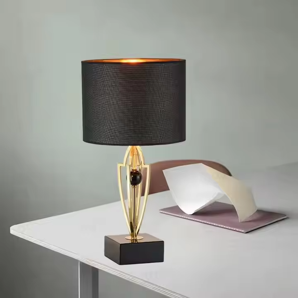 This is a luxurious retro-style table lamp with a golden metal bracket, a black square base, and a black fabric lampshade. It features a grand and elegant design with artistic texture. It is used for local desktop lighting and decoration, creating a luxurious retro ambiance. It is suitable for luxury-style home bedrooms, high-end hotel guest rooms, art exhibition halls and other places.