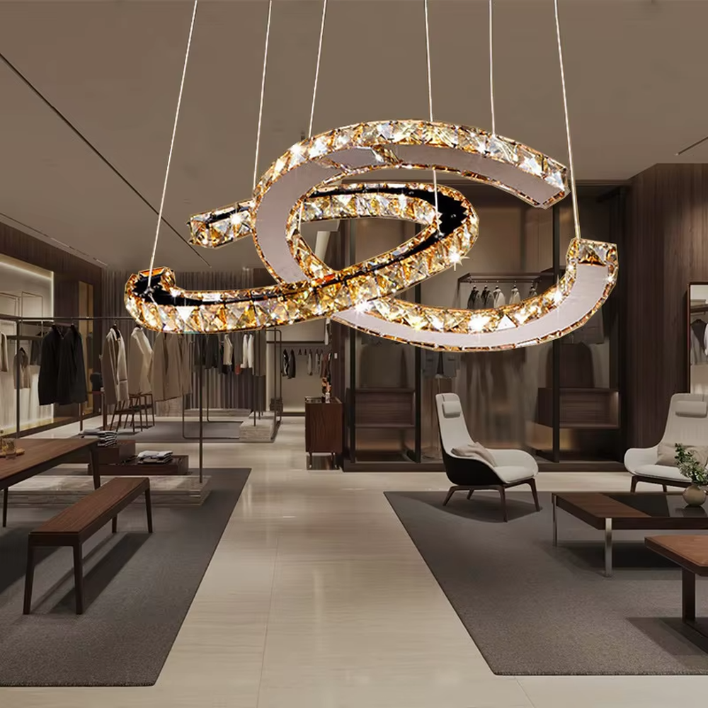 This modern light luxury interwoven ring crystal chandelier consists of multiple crystal-embedded metal rings interlaced and nested, suspended by silver cords. When lit, light refracts through the crystal to emit a brilliant and dynamic glow, combining a futuristic feel with an ambient atmosphere. Ideal for bedrooms, living rooms, light luxury apartments, and other spaces, it adds an exquisite and sophisticated touch to modern minimalist or light luxury home environments.
