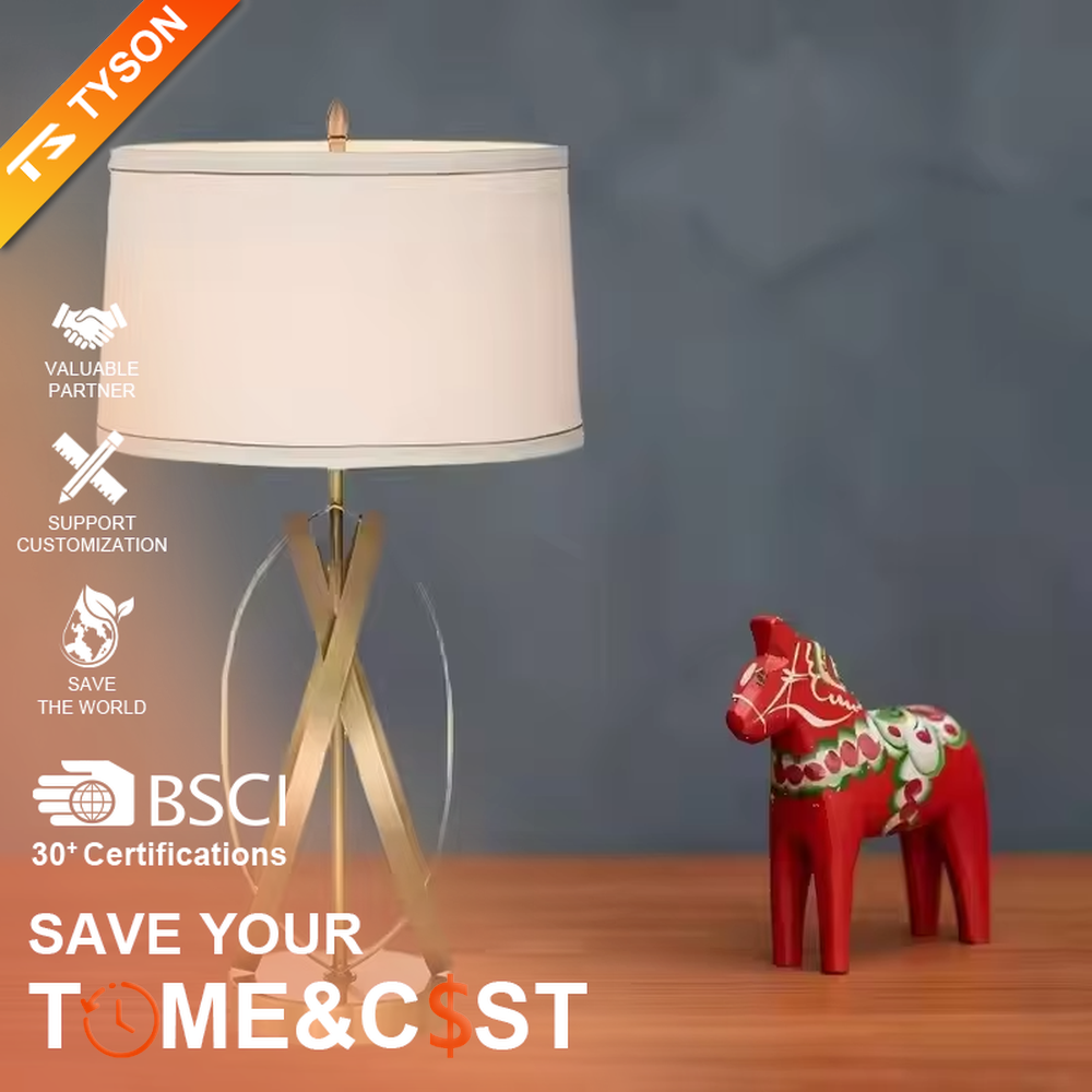 This is a luxury-style table lamp with golden crossed metal brackets and a beige fabric lampshade. It features a simple and elegant design with excellent texture. It is used for local desktop lighting and decoration, creating a luxurious and warm ambiance. It is suitable for luxury-style home bedroom bedside tables, high-end hotel guest rooms, modern office spaces and other places.