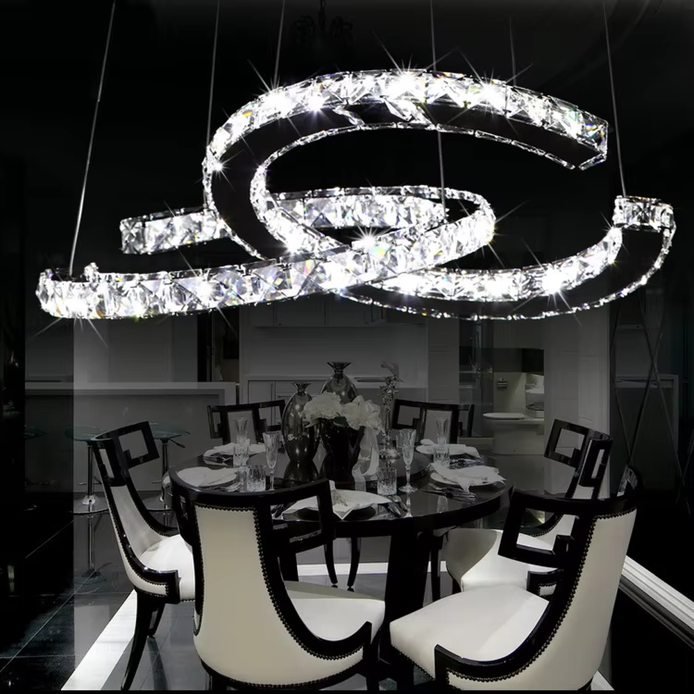 This modern light luxury interwoven ring crystal chandelier consists of multiple crystal-embedded metal rings interlaced and nested, suspended by silver cords. When lit, light refracts through the crystal to emit a brilliant and dynamic glow, combining a futuristic feel with an ambient atmosphere. Ideal for bedrooms, living rooms, light luxury apartments, and other spaces, it adds an exquisite and sophisticated touch to modern minimalist or light luxury home environments.
