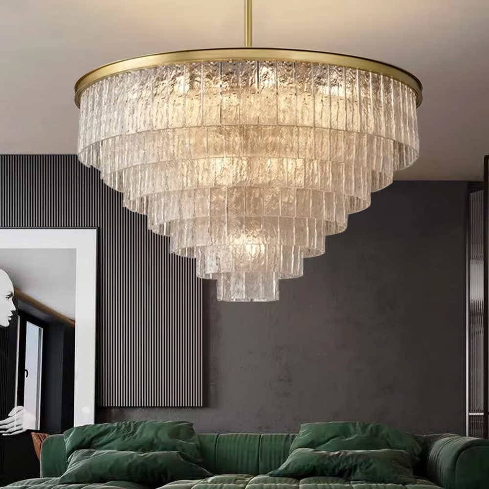 This modern light luxury layered conical chandelier features a gold metal top frame, with multiple layers of textured glass strips hanging down to form a conical layered shape. When lit, light refracts through the glass to emit a brilliant and soft glow, combining a luxurious texture with an ambient atmosphere. Ideal for high-ceiling living rooms, villas, light luxury apartments, and other spaces, it adds an exquisite and sophisticated touch to modern minimalist or light luxury home environments.
