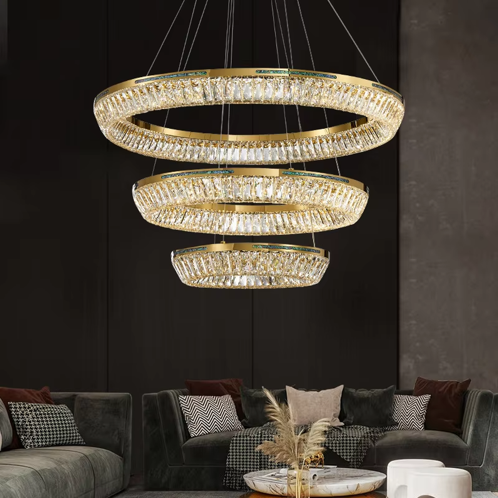 This modern light luxury multi-layered ring crystal chandelier features a gold metal frame, with each ring inlaid with transparent long crystals arranged in concentric circles. When lit, light refracts through the crystal to emit a brilliant and luxurious glow, combining layered design with an ambient atmosphere. Ideal for high-ceiling living rooms, villa foyers, hotel lobbies, and other spaces, it adds an elegant and exquisite touch to modern light luxury or European-style luxury environments.