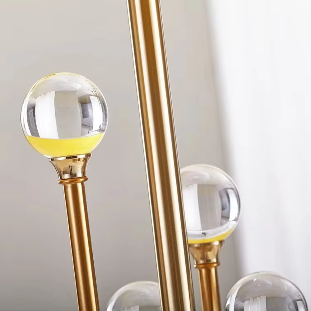 This is a modern luxury-style table lamp with a golden metal stand, multiple spherical decorations, and a beige fabric lampshade that transmits light softly. It has an exquisite and layered design. It is used for local desktop lighting and decoration, combining practicality and aesthetics. It is suitable for modern home living room side tables, bedroom bedside tables, as well as high-end hotel guest rooms, luxury cafes and other places.