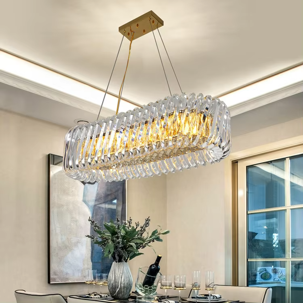 This modern light luxury linear crystal chandelier features a gold metal ceiling base, enclosed by wavy transparent crystal strips to form a full linear shape. When lit, light refracts through the crystal to emit a brilliant and soft glow, combining a transparent texture with an ambient atmosphere. Ideal for dining rooms, bars, light luxury apartments, and other spaces, it adds an exquisite and sophisticated touch to modern minimalist or light luxury home environments.