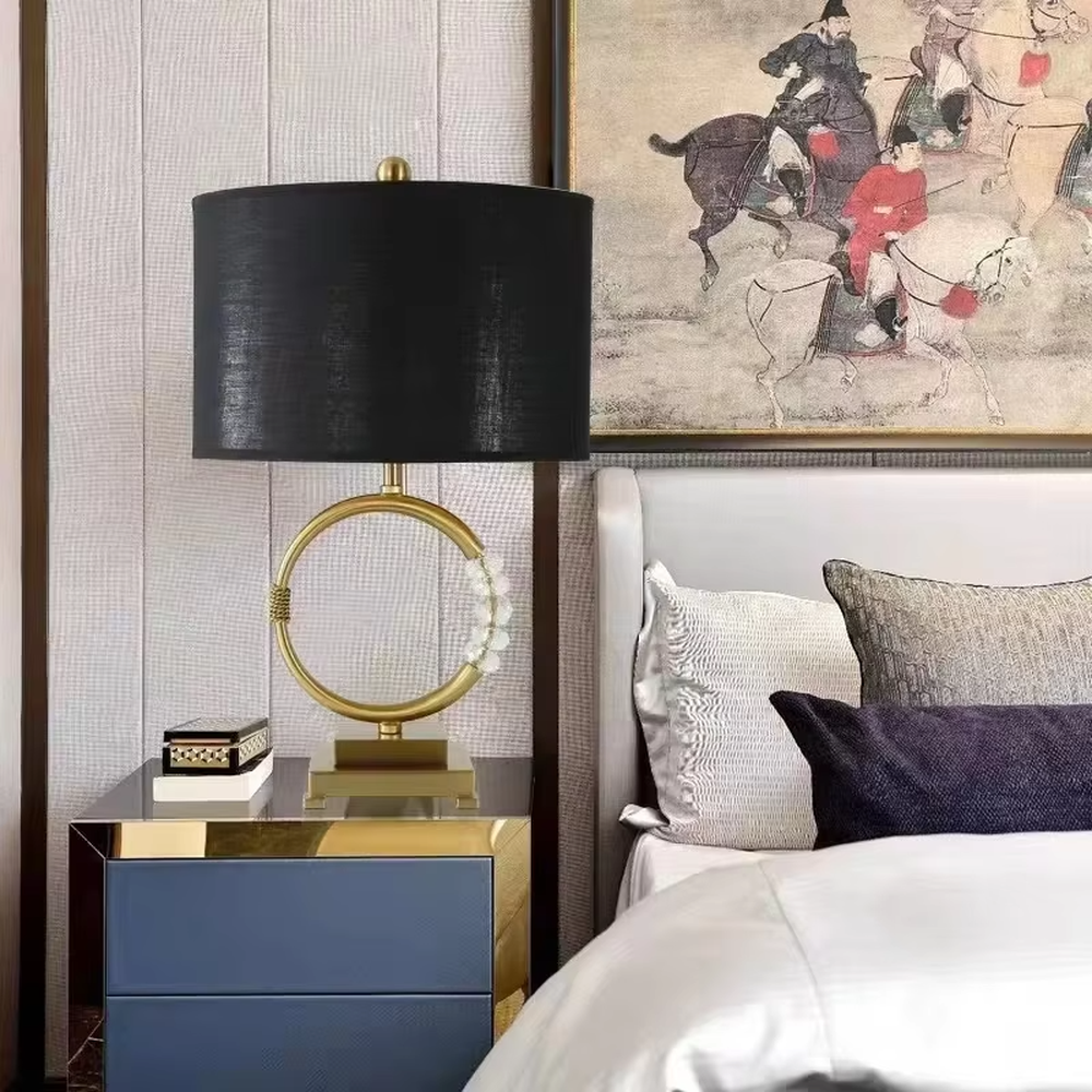 This is a luxurious retro-style table lamp with a golden circular base, a black fabric lampshade, and crystal elements, featuring an elegant and grand design. It is used for local desktop lighting and decoration, enhancing the luxurious retro ambiance of the space. It is suitable for luxury-style home living room side tables, high-end hotel guest rooms, retro-style clubs and other places.