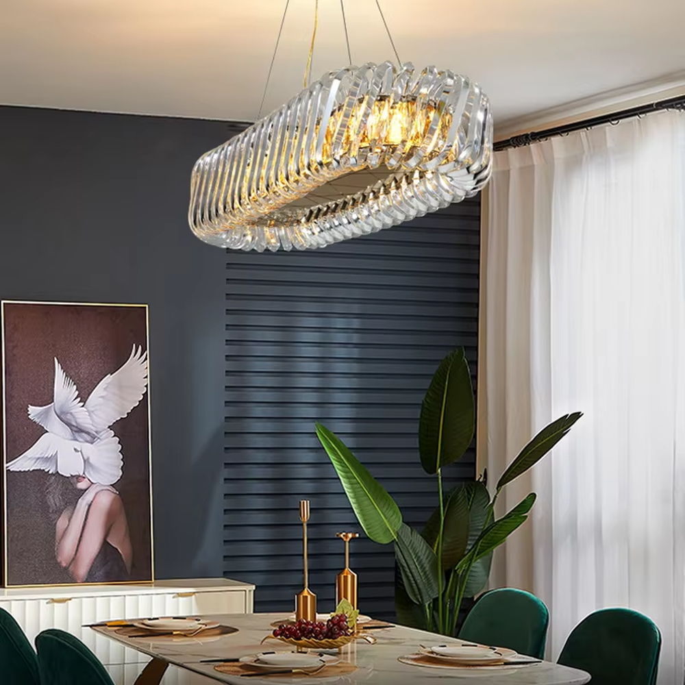 This modern light luxury linear crystal chandelier features a gold metal ceiling base, enclosed by wavy transparent crystal strips to form a full linear shape. When lit, light refracts through the crystal to emit a brilliant and soft glow, combining a transparent texture with an ambient atmosphere. Ideal for dining rooms, bars, light luxury apartments, and other spaces, it adds an exquisite and sophisticated touch to modern minimalist or light luxury home environments.
