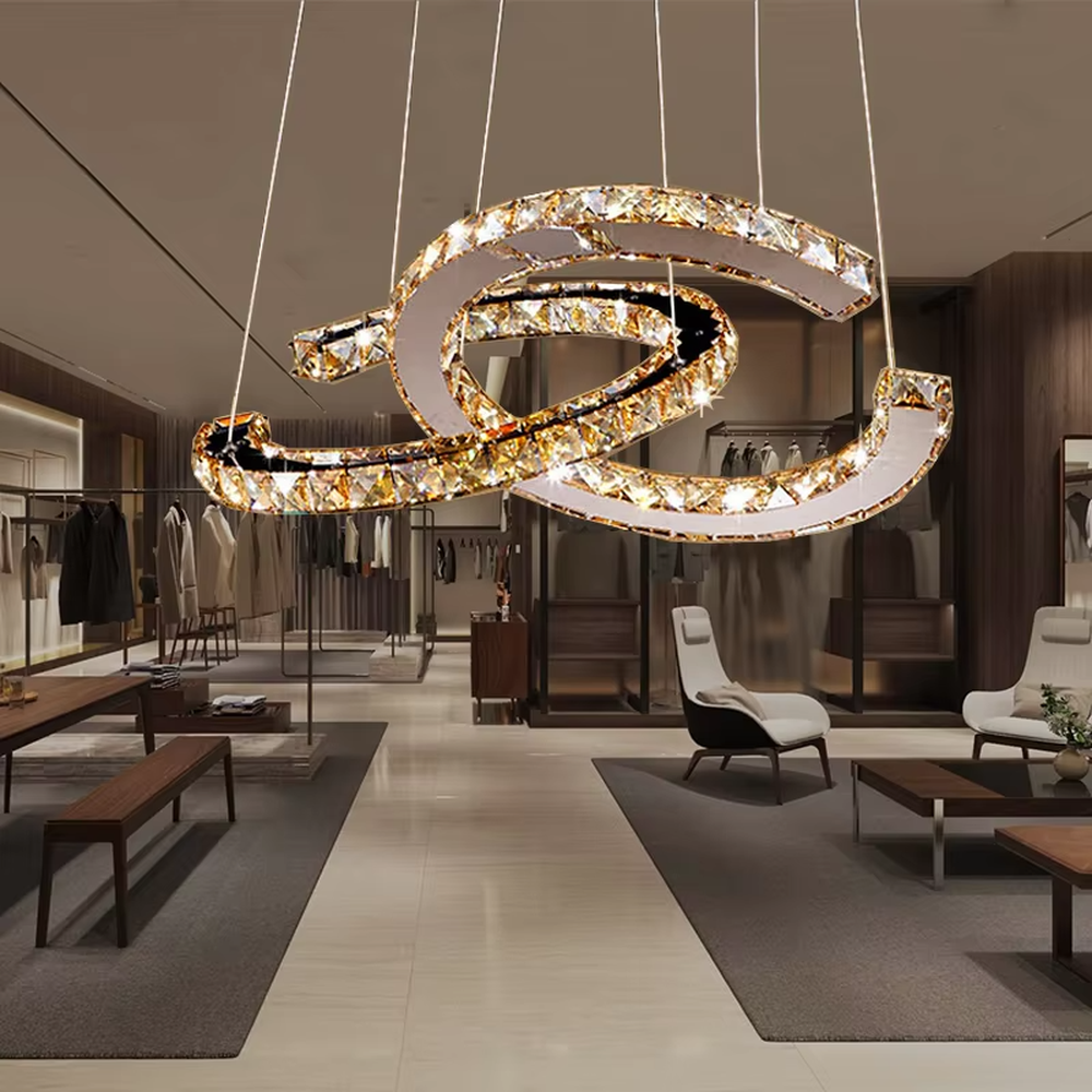 This modern light luxury interwoven ring crystal chandelier consists of multiple crystal-embedded metal rings interlaced and nested, suspended by silver cords. When lit, light refracts through the crystal to emit a brilliant and dynamic glow, combining a futuristic feel with an ambient atmosphere. Ideal for bedrooms, living rooms, light luxury apartments, and other spaces, it adds an exquisite and sophisticated touch to modern minimalist or light luxury home environments.
