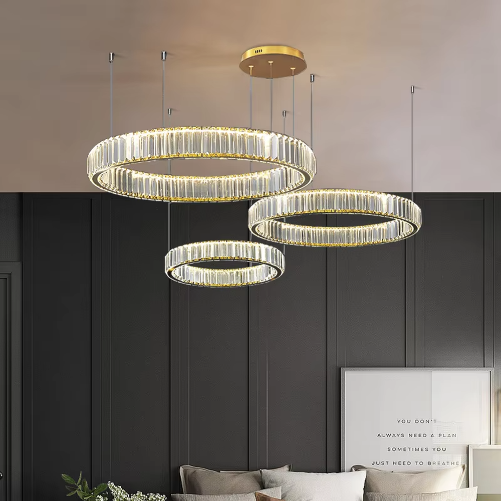 This modern light luxury multi-layer circular crystal chandelier features gold metal frames, inlaid with transparent long crystals to create three groups of staggered circular shapes. When lit, light refracts through the crystals to emit a brilliant and soft glow, combining a layered texture with an ambient atmosphere. Ideal for high-ceiling living rooms, duplex apartments, light luxury apartments, and other spaces, it adds an exquisite and sophisticated touch to modern minimalist or light luxury home environments.