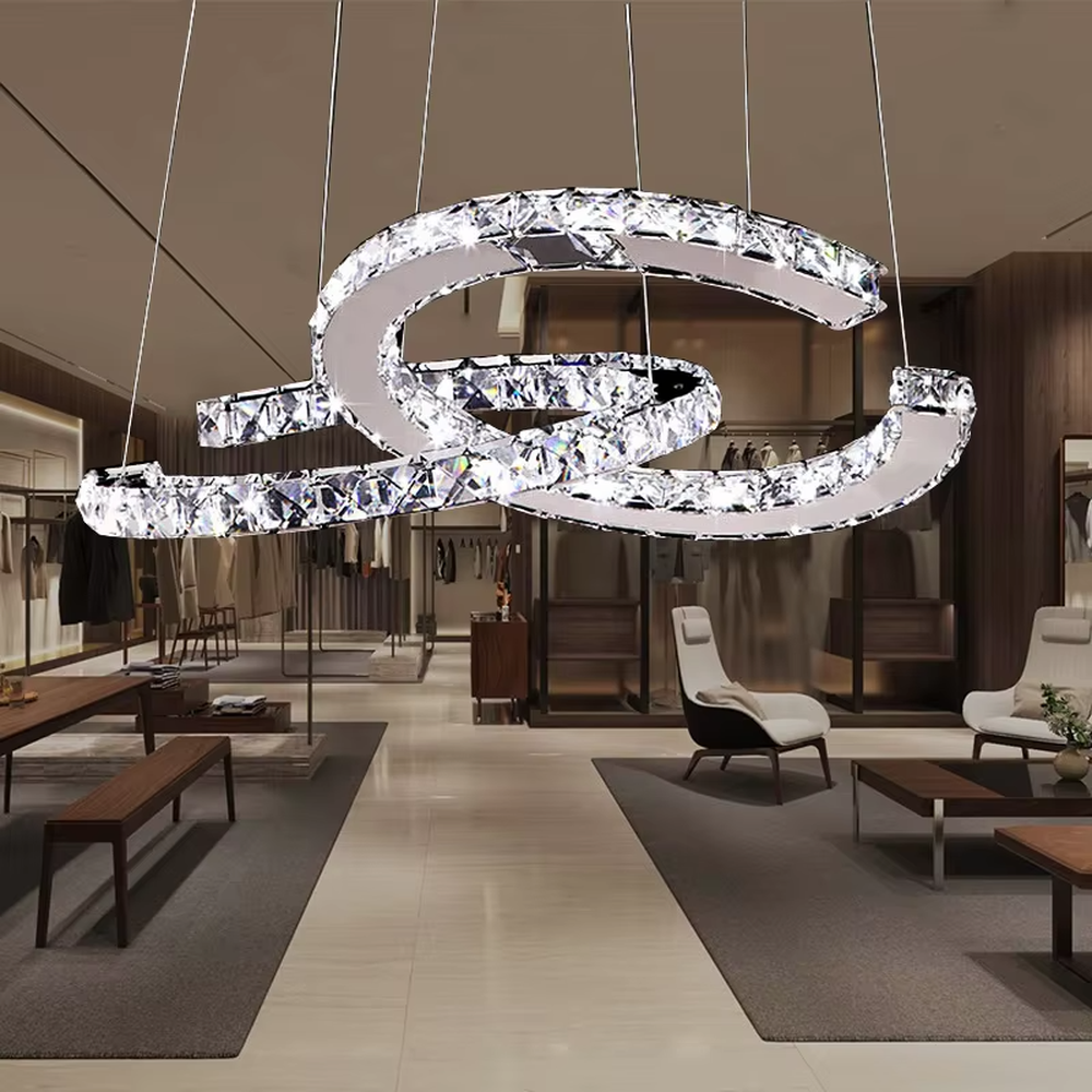 This modern light luxury interwoven ring crystal chandelier consists of multiple crystal-embedded metal rings interlaced and nested, suspended by silver cords. When lit, light refracts through the crystal to emit a brilliant and dynamic glow, combining a futuristic feel with an ambient atmosphere. Ideal for bedrooms, living rooms, light luxury apartments, and other spaces, it adds an exquisite and sophisticated touch to modern minimalist or light luxury home environments.
