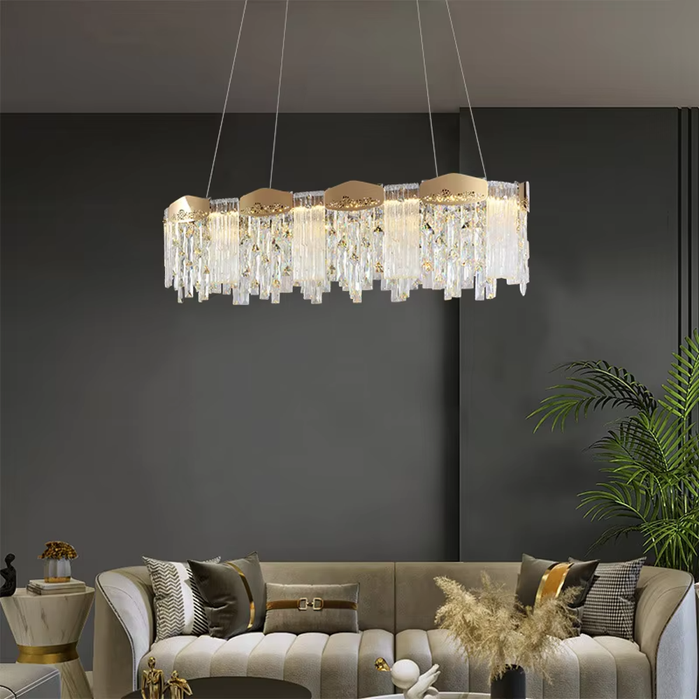 This modern light luxury linear crystal chandelier features a gold metal frame, with dense transparent long crystals hanging down and hollow-textured metal decorative blocks on top. When lit, light refracts through the crystal to emit a brilliant and soft glow, combining an exquisite texture with an ambient atmosphere. Ideal for dining rooms, bars, light luxury apartments, and other spaces, it adds an exquisite and sophisticated touch to modern minimalist or light luxury home environments.
