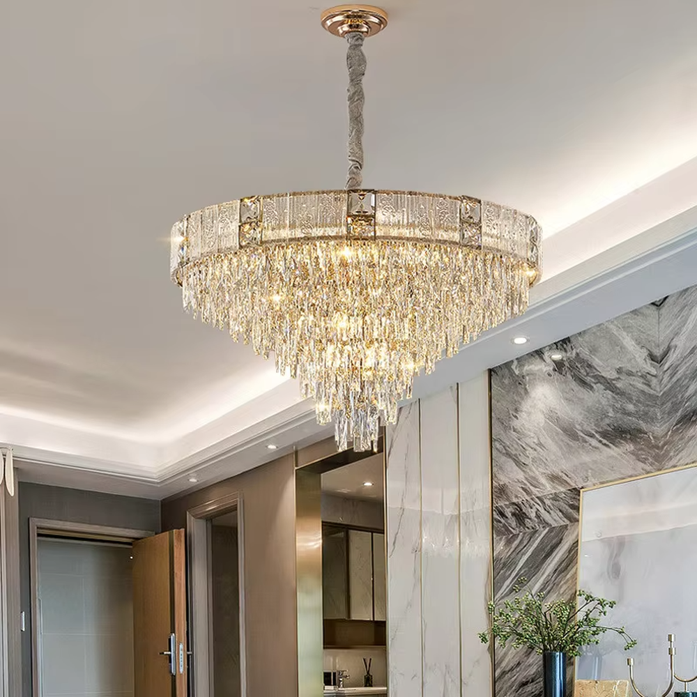 This light luxury and grand multi-layer conical crystal chandelier features a gold metal frame, with vertical-textured glass lampshades on the upper layer and multiple layers of transparent crystal tassels hanging below, creating a full conical shape. When lit, light refracts through the crystal to emit a brilliant and luxurious glow, combining elegant texture with an ambient atmosphere. Ideal for living rooms, dining rooms, villa high-ceiling spaces, and other areas, it adds an elegant and exquisite touch to European light luxury or modern luxury home environments.