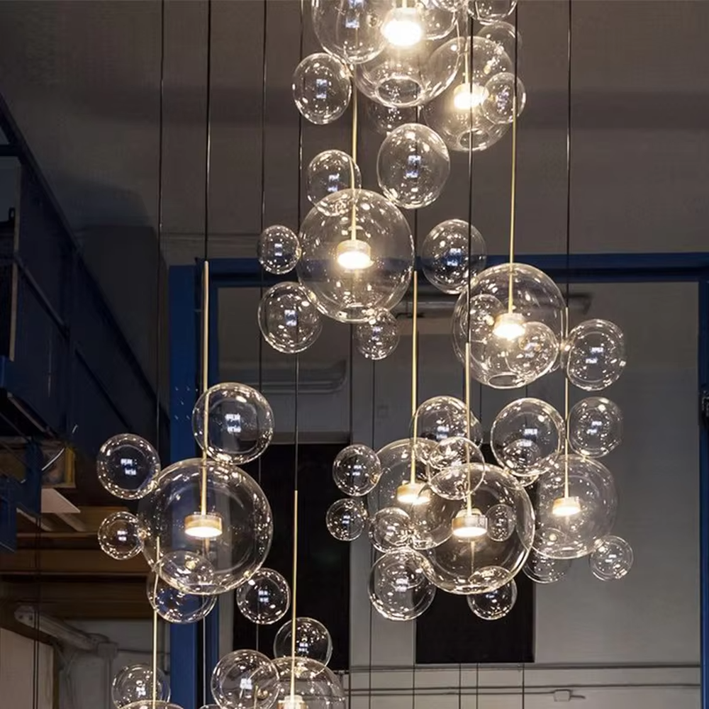 Modern art bubble cluster chandelier, featuring a cloud-like arrangement of transparent glass bubbles paired with black and gold suspension wires. Light refracts through the bubbles to create a soft and translucent glow, combining a dreamy feel and artistic ambiance, making it a high-end decorative lighting fixture that elevates the space's style.