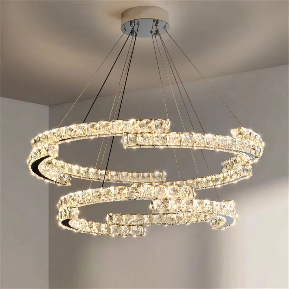 This modern light luxury double-ring interwoven crystal chandelier features a silver metal base, inlaid with transparent crystals to create a dynamic double-ring interwoven shape. When lit, light refracts through the crystal to emit a brilliant and dynamic glow, combining a futuristic feel with an ambient atmosphere. Ideal for living rooms, dining rooms, light luxury apartments, and other spaces, it adds an exquisite and sophisticated touch to modern minimalist or light luxury home environments.
