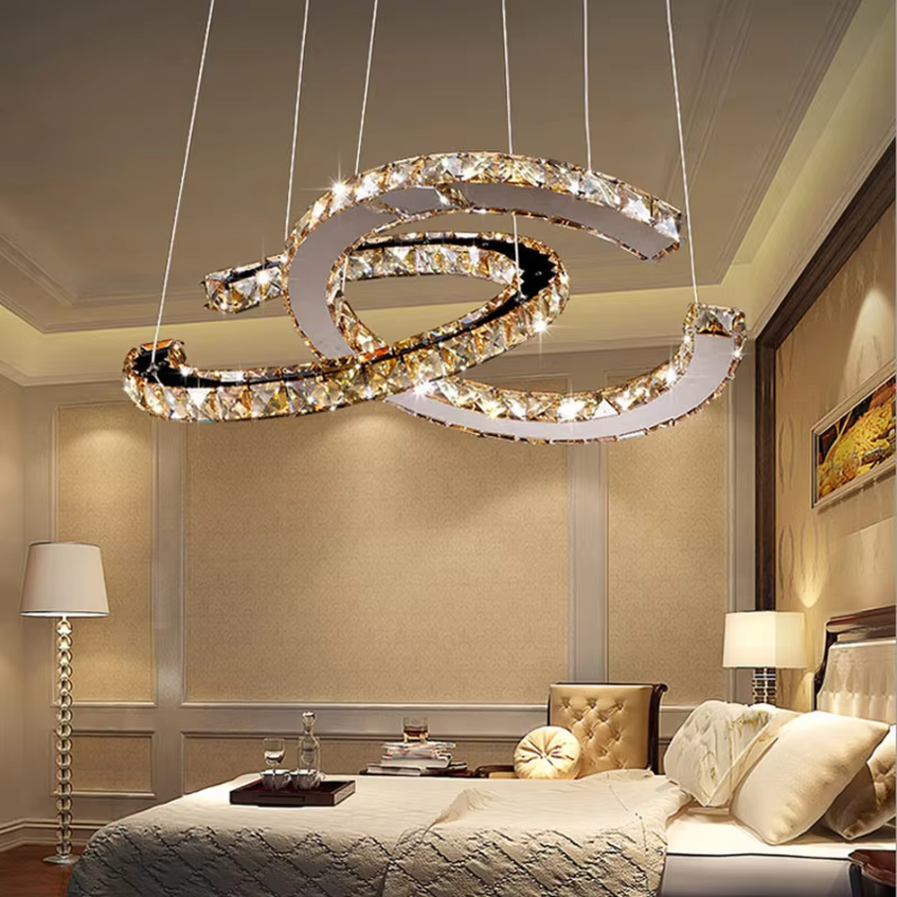 This modern light luxury interwoven ring crystal chandelier consists of multiple crystal-embedded metal rings interlaced and nested, suspended by silver cords. When lit, light refracts through the crystal to emit a brilliant and dynamic glow, combining a futuristic feel with an ambient atmosphere. Ideal for bedrooms, living rooms, light luxury apartments, and other spaces, it adds an exquisite and sophisticated touch to modern minimalist or light luxury home environments.
