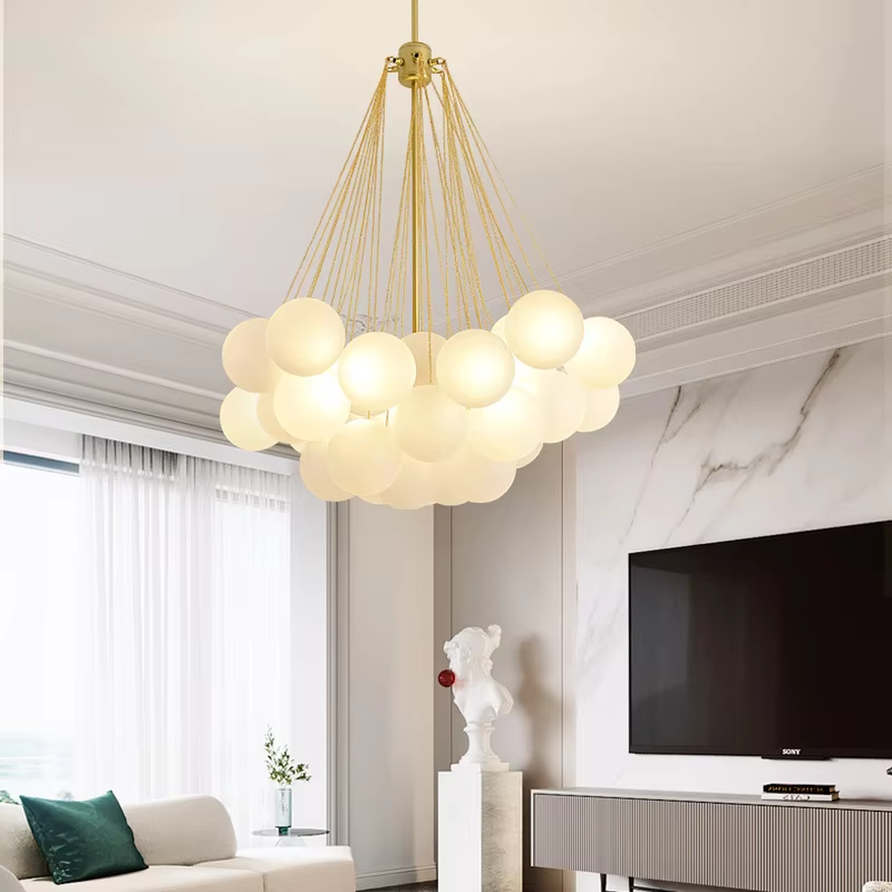 This modern light luxury milk-white cluster chandelier features a gold metal frame, paired with multiple milky white frosted glass ball lampshades arranged in a cloud-like staggered layout. When lit, it emits a soft and gentle glow, combining romantic ambiance with design appeal. Ideal for living rooms, dining rooms, bedrooms, and other spaces, it adds a warm and exquisite touch to modern light luxury, Nordic, or minimalist home environments.