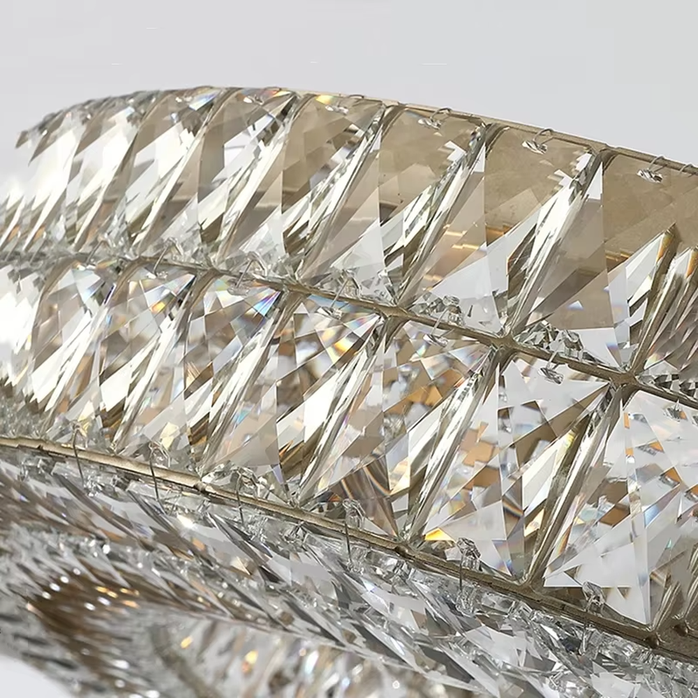 This modern light luxury linear crystal chandelier features a gold metal frame, inlaid with two layers of cut crystal blocks to form a square shape. When lit, light refracts through the crystals to emit a brilliant and luxurious glow, combining an exquisite texture with an ambient atmosphere. Ideal for dining rooms, bars, light luxury apartments, and other spaces, it adds an exquisite and sophisticated touch to modern minimalist or light luxury home environments.
