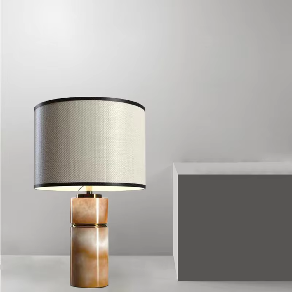This is a light luxury minimalist table lamp, with a beige textured fabric lampshade (embellished with black trim) paired with a copper-gold layered texture base. It has an elegant and high-end style, with soft and warm lighting, creating a light luxury minimalist atmosphere.