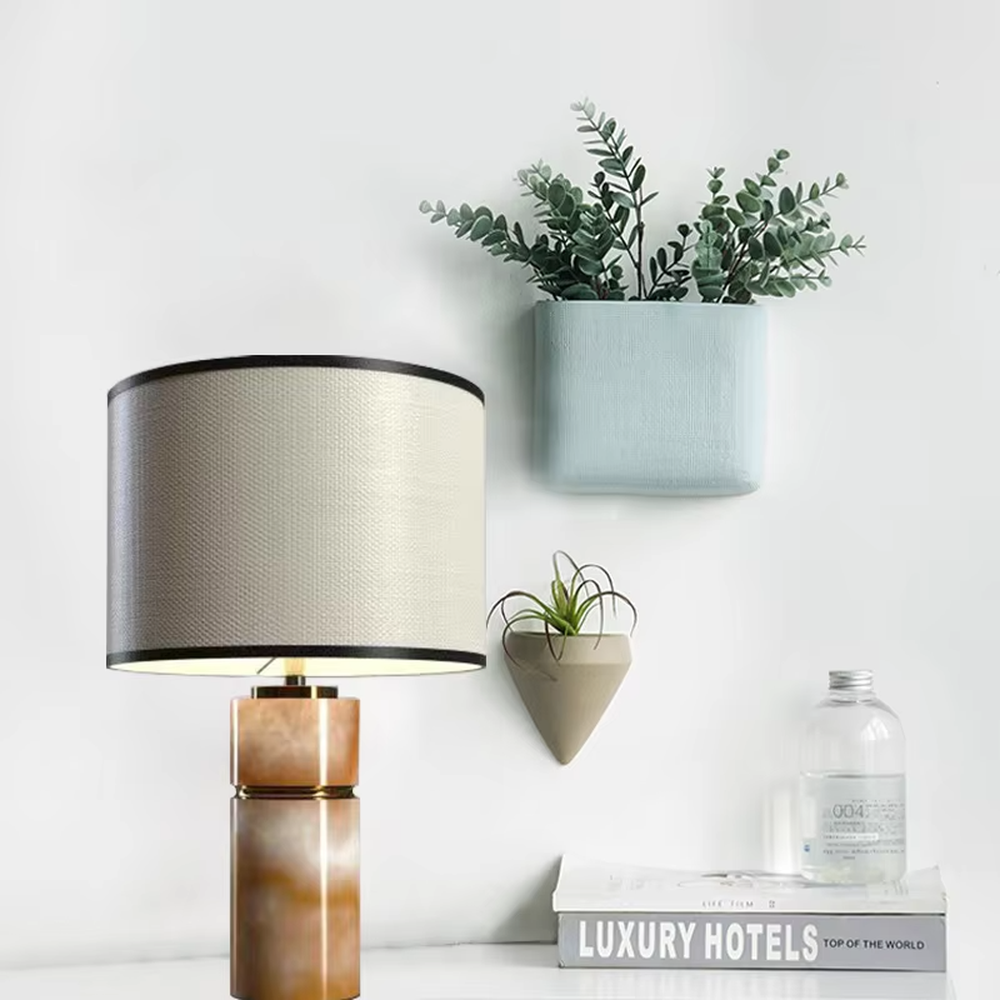 This is a light luxury minimalist table lamp, with a beige textured fabric lampshade (embellished with black trim) paired with a copper-gold layered texture base. It has an elegant and high-end style, with soft and warm lighting, creating a light luxury minimalist atmosphere.