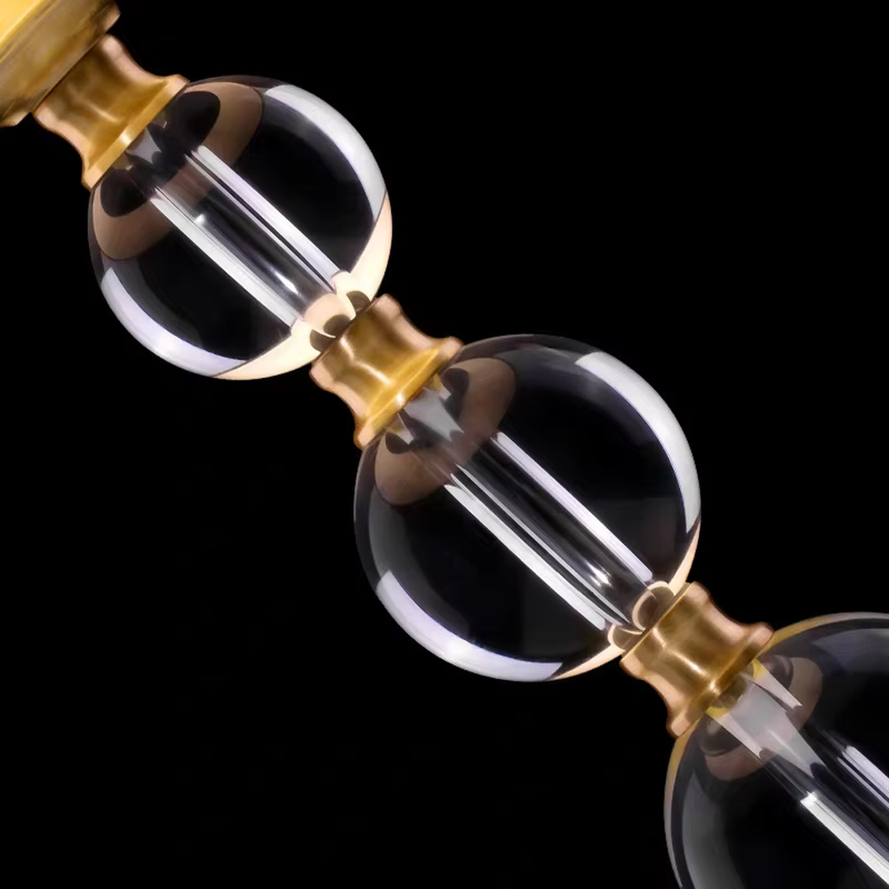 This is a light luxury exquisite crystal ball column table lamp, with a golden metal base and connectors, paired with transparent crystal ball columns and a beige fabric lampshade. It features a light luxury and exquisite design, with warm and soft lighting. It is used for local desktop lighting and decoration, creating a light luxury elegant atmosphere. Suitable for light luxury-style bedroom bedside tables, modern minimalist living room side tables, high-end hotel guest rooms and other places.