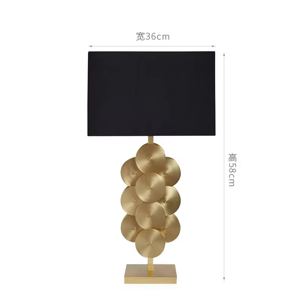 This is a luxury-style black and gold table lamp, with a golden disc-stacked base and a black square fabric lampshade, featuring a minimalist and grand design with strong luxury texture. It is used for local desktop lighting and decoration, creating a luxury and modern atmosphere. It is suitable for luxury-style home bedroom bedside tables, high-end hotel guest rooms, modern minimalist living room side tables and other places.