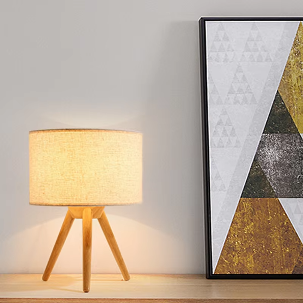 Natural minimalist-style wooden tripod table lamp, beige linen lampshade + solid wood stand, soft and warm lighting, creating a comfortable natural atmosphere.