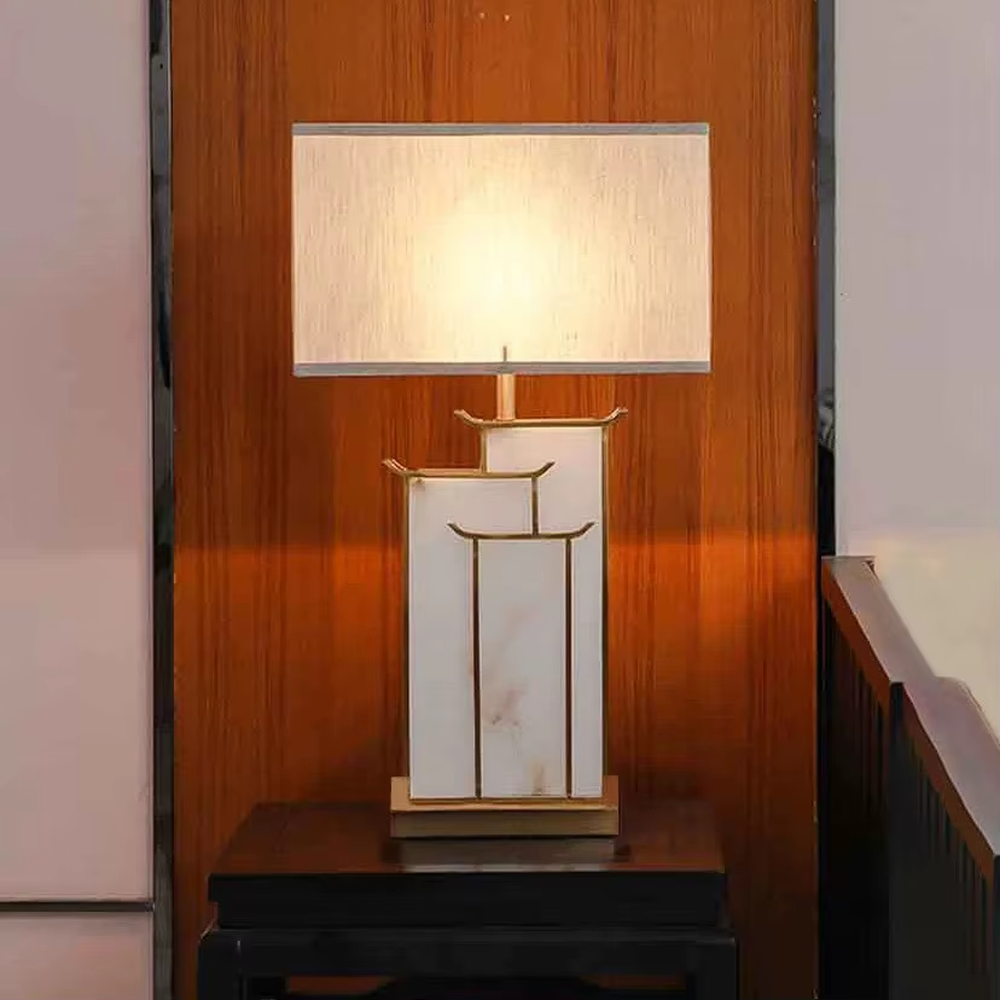 New Chinese light luxury gold frame ink texture table lamp, gold window lattice-like metal frame + ink texture panel + beige fabric lampshade, soft lighting, creating an elegant new Chinese atmosphere.