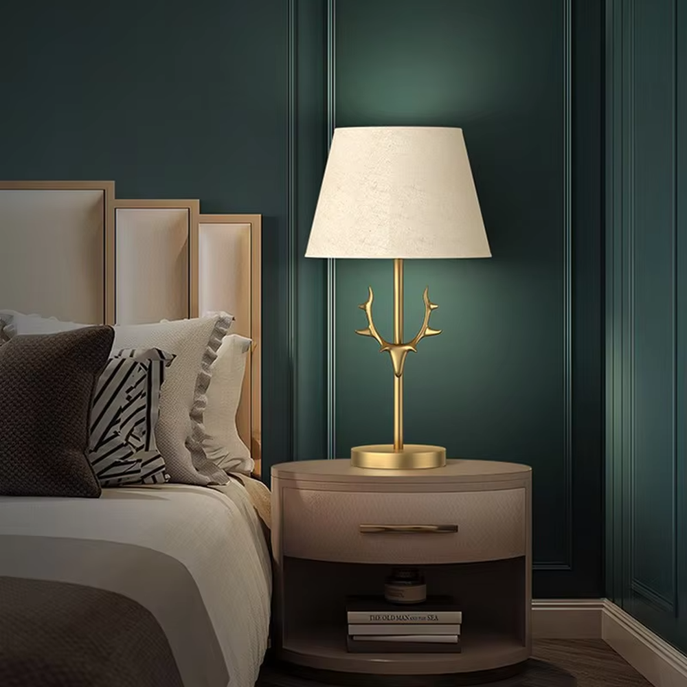 Light luxury golden antler-shaped table lamp, white cylindrical fabric lampshade + golden base, soft and warm lighting, creating a natural elegant atmosphere.