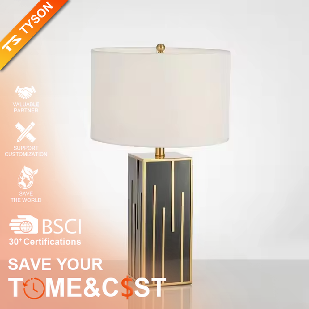 This is a luxury geometric - shaped table lamp with a black - gold geometric base (decorated with gold lines) and a white cylindrical fabric lampshade, featuring a minimalist luxury design with strong modern artistic sense. It is used for local desktop lighting and decoration, creating a luxurious and elegant atmosphere. It is suitable for luxury - style home bedroom bedside tables, high - end hotel guest rooms, modern soft decoration display spaces and other places.