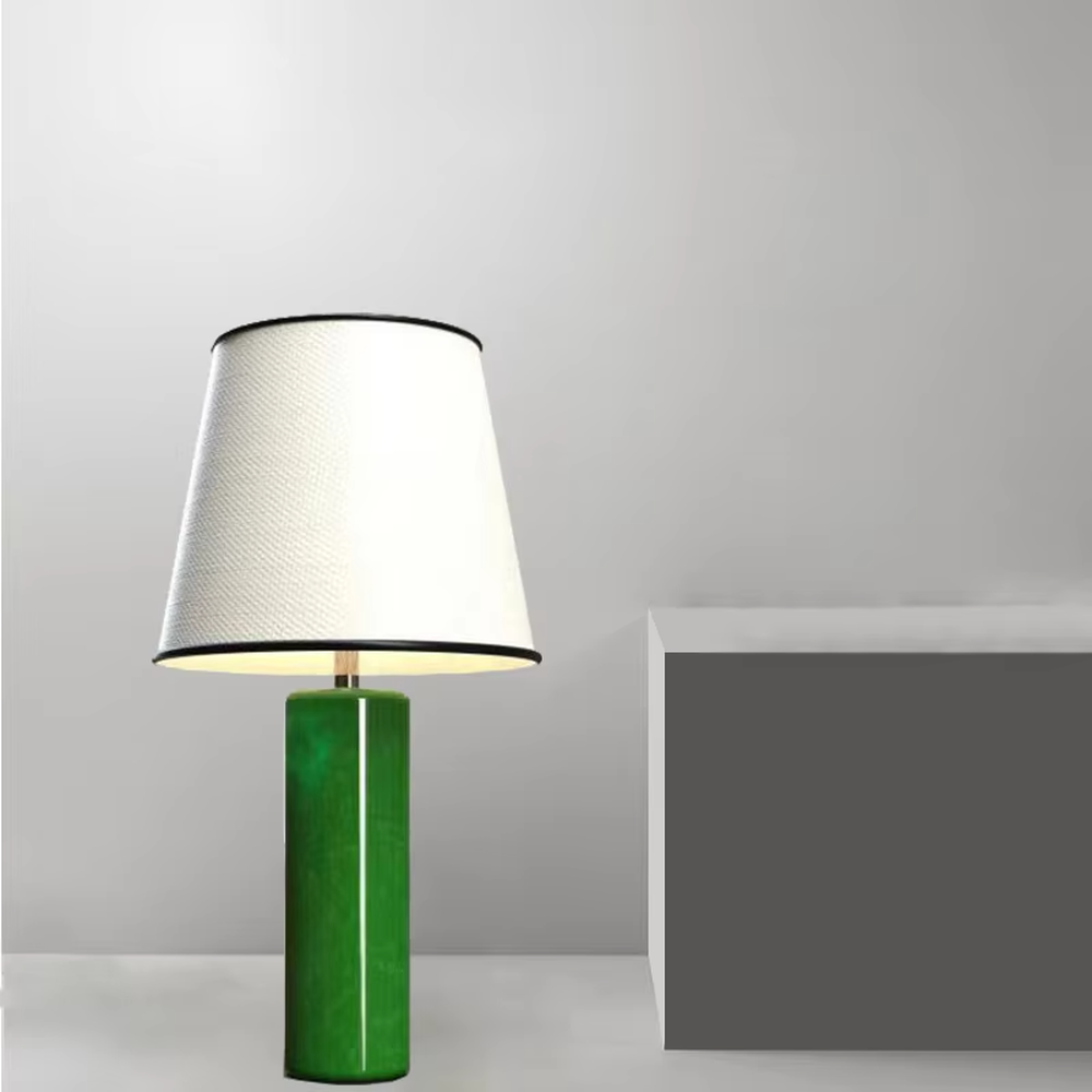 This is a modern fresh-style green cylindrical table lamp, with a green cylindrical base and a white fabric lampshade (black edging), featuring a minimalist modern design and fresh style. It is used for local desktop lighting and decoration, creating a fresh and modern atmosphere. Suitable for modern minimalist bedroom bedside tables, Nordic-style living room side tables, creative studios and other places.