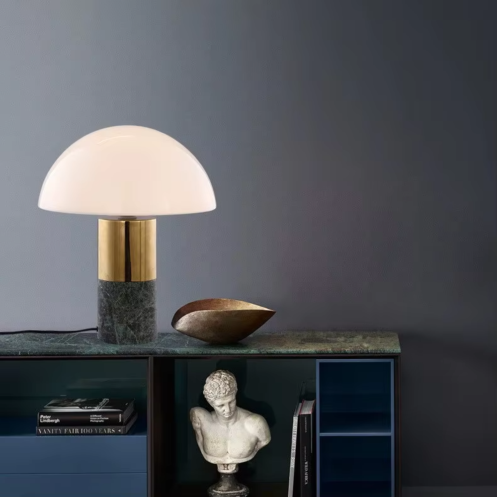 This is a light luxury minimalist hemisphere lampshade table lamp, with a white hemisphere lampshade paired with a golden metal + dark green marble base. It has an exquisite and high-end style, soft and warm lighting, creating a light luxury atmosphere.