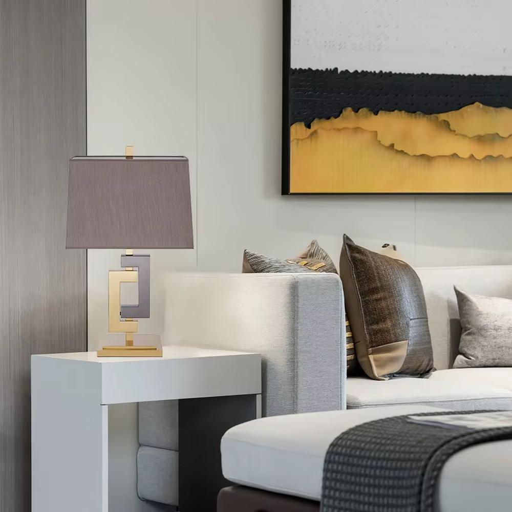 Light luxury gold-gray color-blocking geometric square frame table lamp, gold + dark gray metal geometric stand + dark gray fabric rectangular lampshade, soft and high-end lighting, creating a light luxury modern atmosphere.