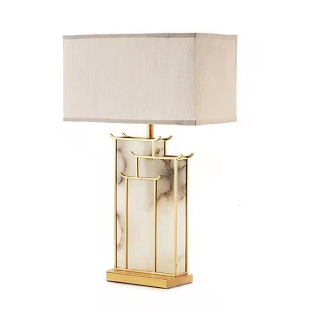 New Chinese light luxury gold frame ink texture table lamp, gold window lattice-like metal frame + ink texture panel + beige fabric lampshade, soft lighting, creating an elegant new Chinese atmosphere.