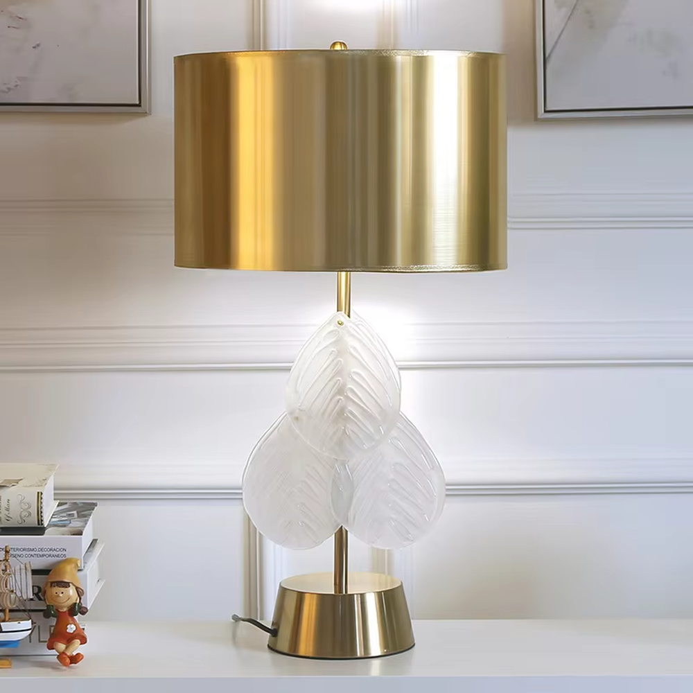 This is a light luxury artistic-style gold and white leaf-decorated table lamp, with a golden metal lampshade and base, paired with transparent leaf-shaped decorations (with texture). It features an exquisite light luxury design, with warm and soft lighting. It is used for local desktop lighting and decoration, creating a light luxury artistic atmosphere. Suitable for light luxury-style bedroom bedside tables, modern minimalist living room side tables, high-end home studies and other places.