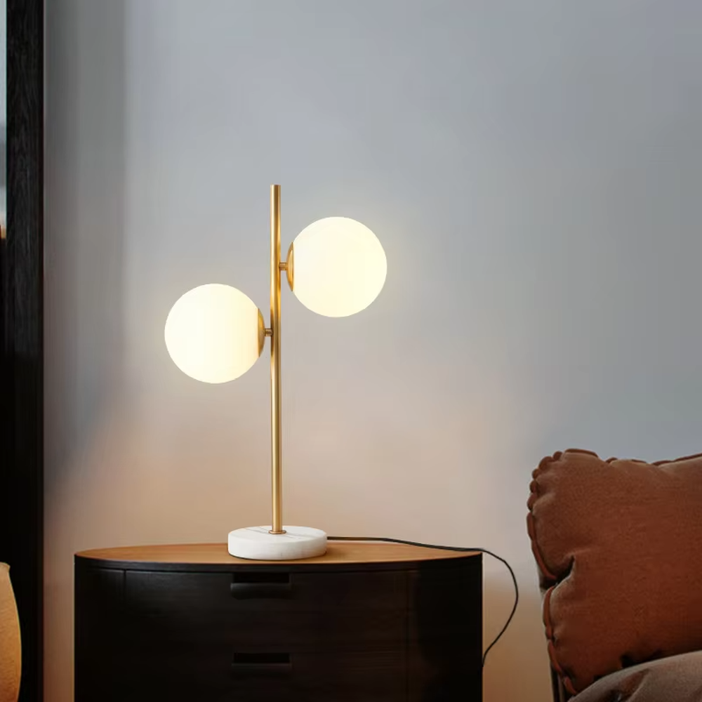 This is a modern light luxury double-ball table lamp, with a golden lamp pole paired with frosted white ball lampshades and a white marble base. The style is simple and exquisite, with soft and warm lighting.