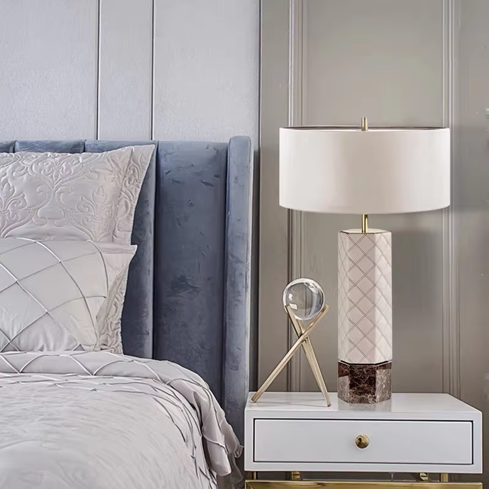 This is a light luxury elegant-style geometric textured column table lamp, with a beige fabric round lampshade, paired with golden metal connectors and a geometric textured column (marble texture at the bottom). It features an exquisite light luxury design, with warm and soft lighting. It is used for local desktop lighting and decoration, creating a light luxury elegant atmosphere. Suitable for light luxury-style bedroom bedside tables, modern minimalist living room side tables, high-end hotel guest rooms and other places.