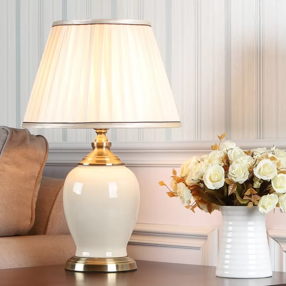 Vintage elegant-style beige pleated fabric lampshade table lamp, white porcelain vase base + golden metal decorations, soft and warm lighting, creating an elegant and cozy atmosphere.