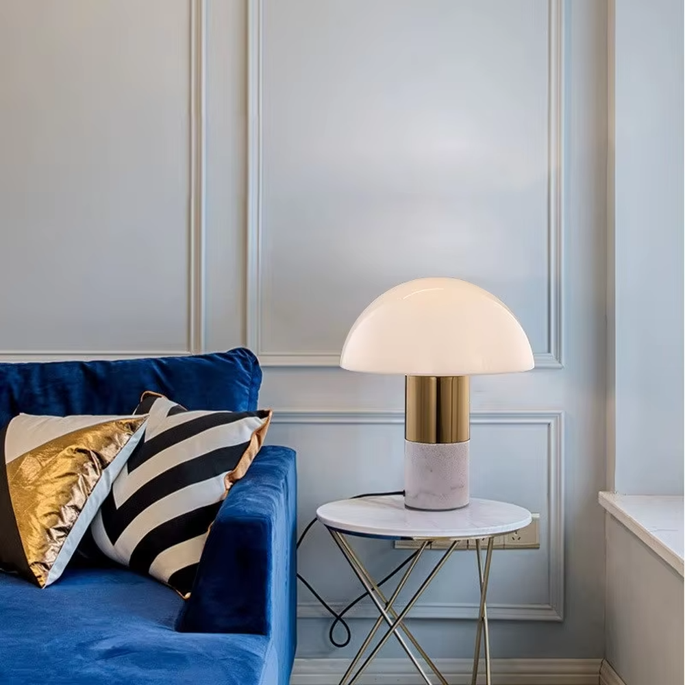 This is a light luxury minimalist hemisphere lampshade table lamp, with a white hemisphere lampshade paired with a golden metal + dark green marble base. It has an exquisite and high-end style, soft and warm lighting, creating a light luxury atmosphere.