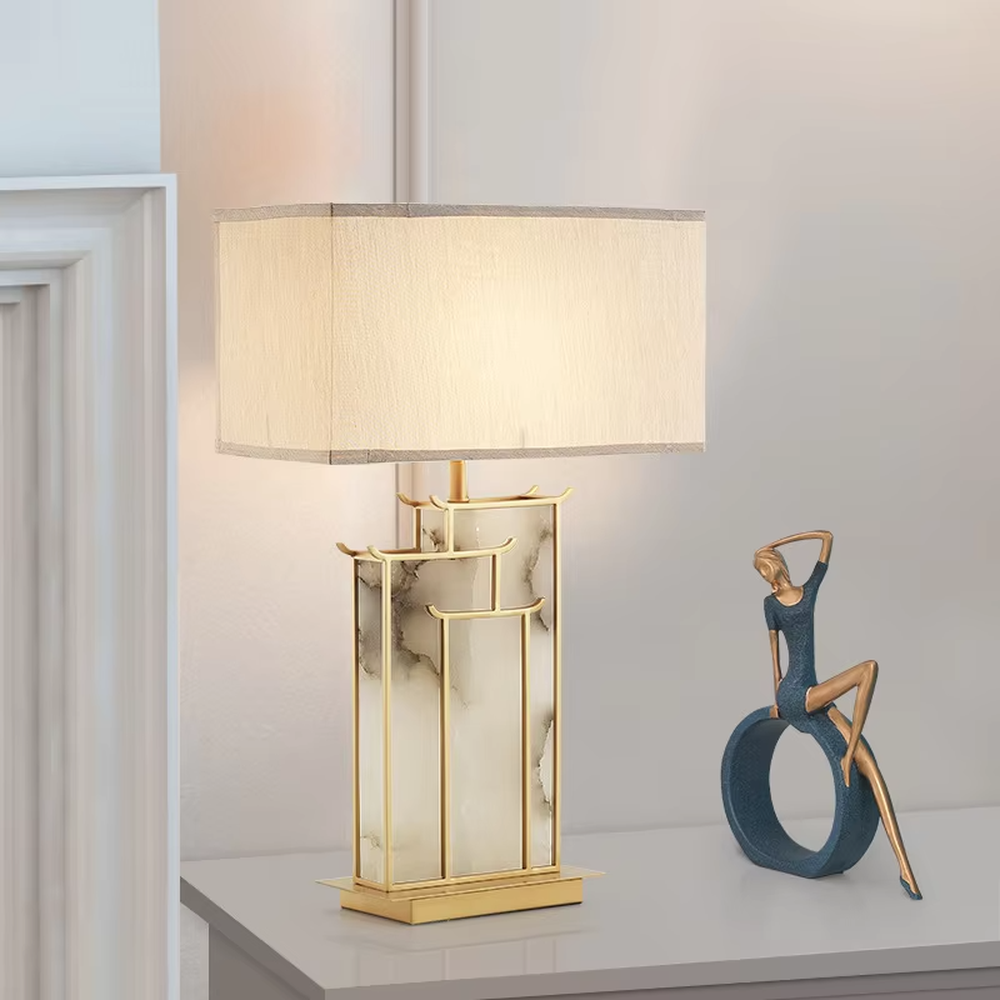 New Chinese light luxury gold frame ink texture table lamp, gold window lattice-like metal frame + ink texture panel + beige fabric lampshade, soft lighting, creating an elegant new Chinese atmosphere.