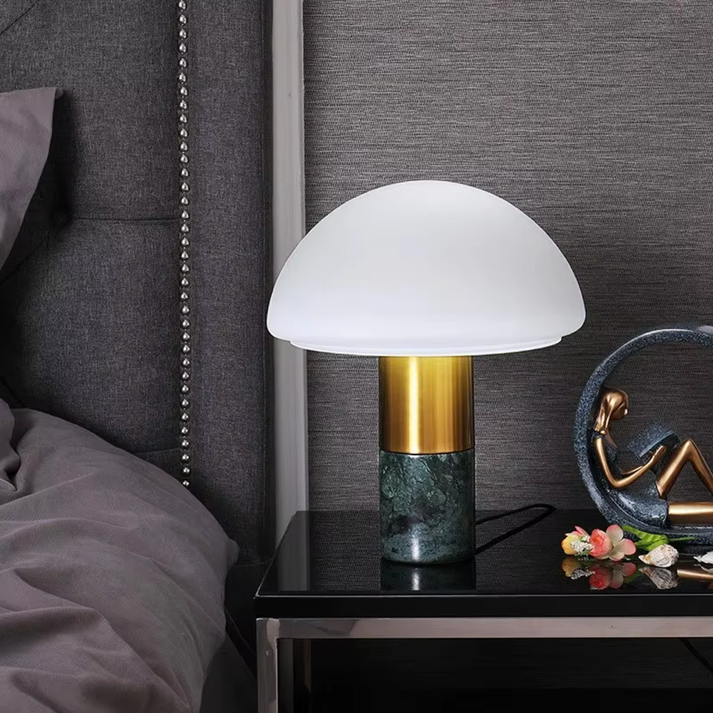This is a light luxury minimalist hemisphere lampshade table lamp, with a white hemisphere lampshade paired with a golden metal + dark green marble base. It has an exquisite and high-end style, soft and warm lighting, creating a light luxury atmosphere.