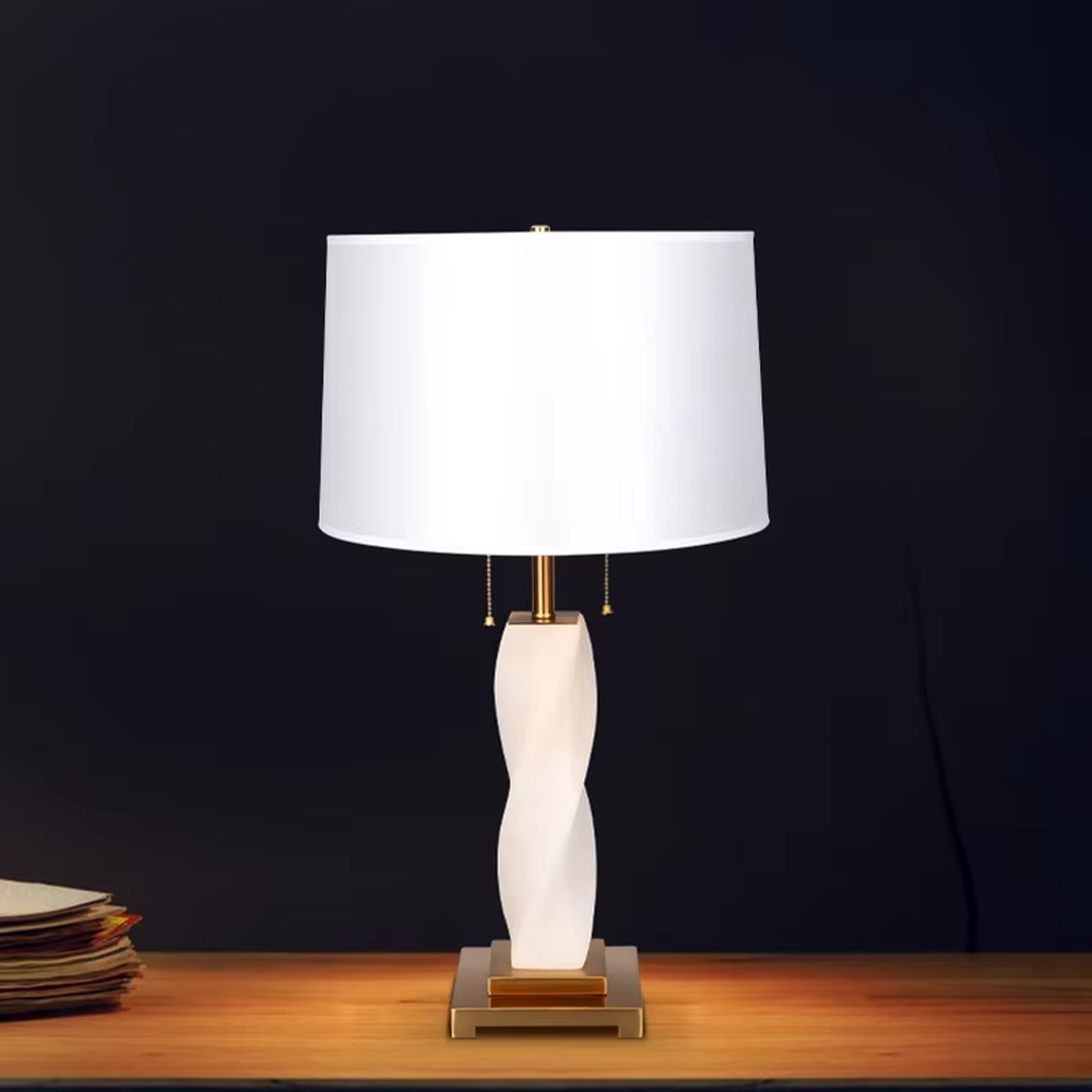 This is a modern artistic twisted table lamp, with a white twisted base, golden metal components, and a white fabric circular lampshade, featuring a strong artistic sense and luxury texture. It is used for local desktop lighting and decoration, creating an artistic luxury atmosphere. It is suitable for modern art home bedroom bedside tables, designer studios, high-end hotel guest rooms and other places.