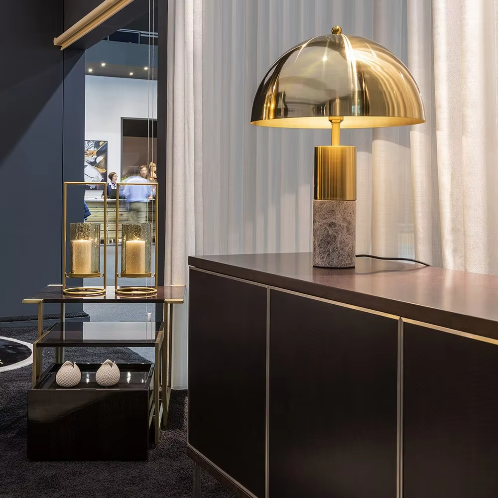 This is a luxury-style gold-brown marble table lamp, with a golden dome lampshade, golden metal pole, and brown marble base, featuring a minimalist and grand design with strong luxury texture. It is used for local desktop lighting and decoration, creating a luxury and modern atmosphere. Suitable for luxury-style home bedroom bedside tables, high-end hotel guest rooms, modern minimalist living room side tables and other places.