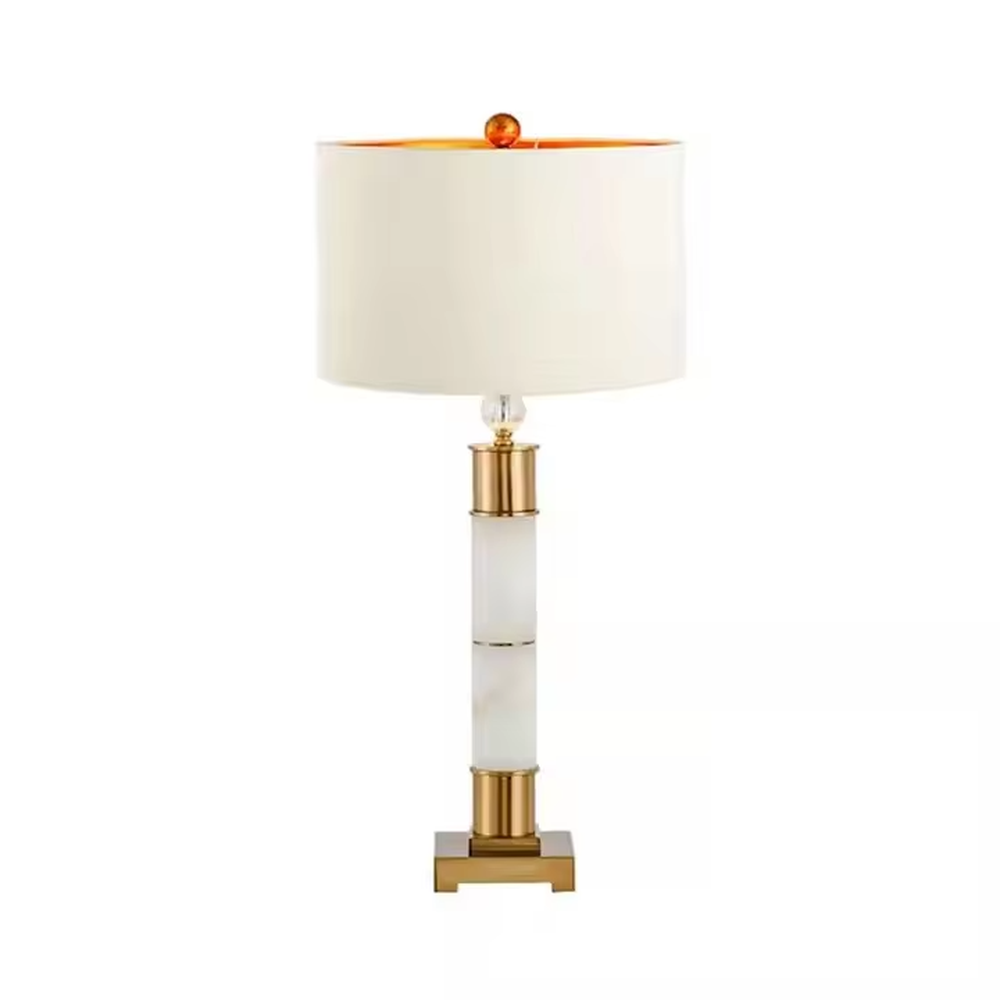 This is a luxury-style gold and white table lamp, combining golden metal and white cylinder, with a beige fabric circular lampshade, featuring a minimalist and grand design with strong luxury texture. It is used for local desktop lighting and decoration, creating a luxury and warm atmosphere. It is suitable for luxury-style home bedroom bedside tables, high-end hotel guest rooms, modern minimalist living room side tables and other places.