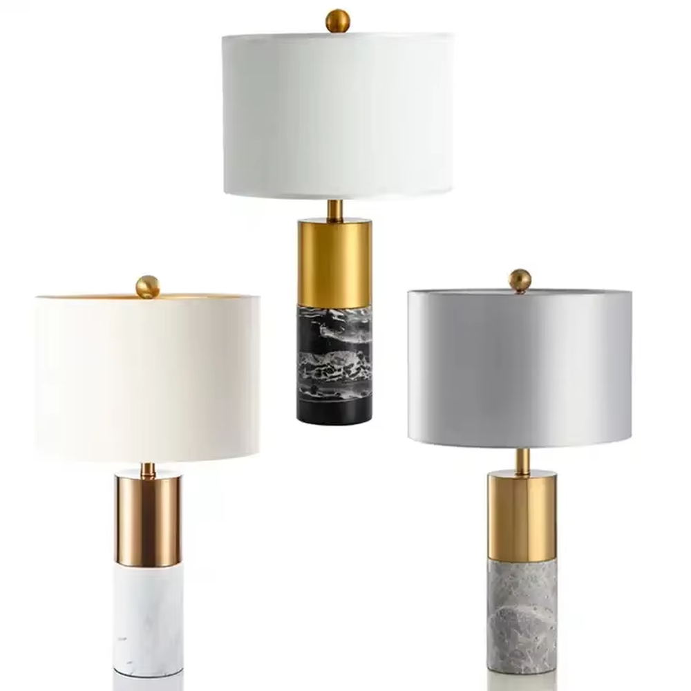 Light luxury gold-decor white marble cylindrical base table lamp, beige fabric cylindrical lampshade, soft warm light, creating a simple high-end light luxury atmosphere.