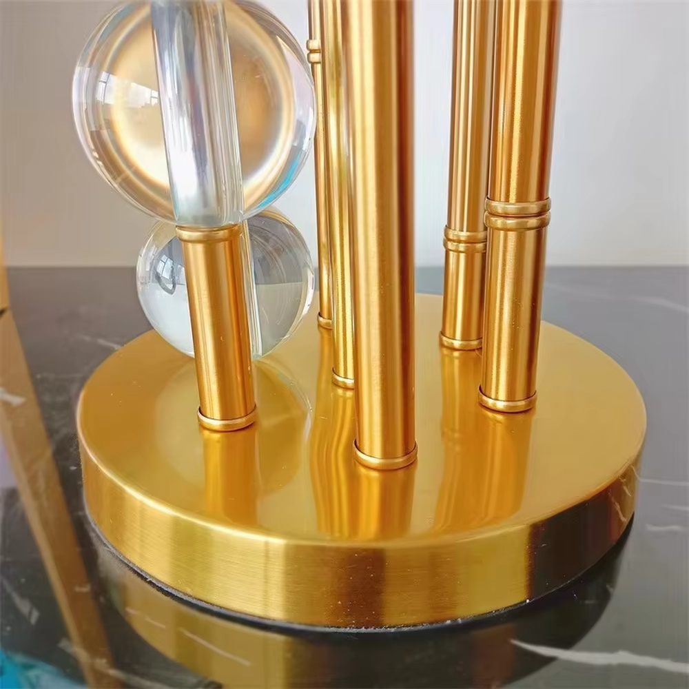 This is a luxury black-gold crystal table lamp, with a golden metal column (with multiple thin columns design) and transparent crystal balls, a black cylindrical fabric lampshade, featuring a modern luxury design with high-quality texture. It is used for local desktop lighting and decoration, creating a high-end luxury atmosphere. It is suitable for luxury-style home bedroom bedside tables, high-end hotel guest rooms, modern soft decoration display spaces and other places.