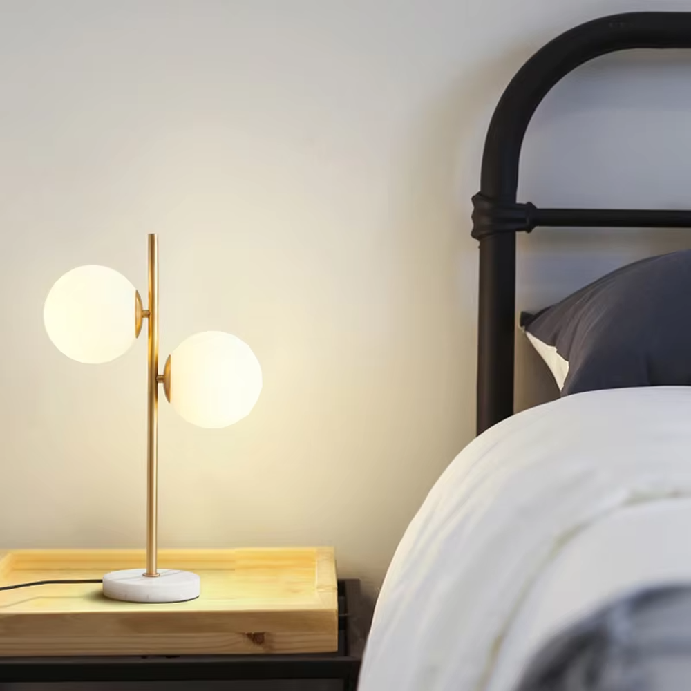 This is a modern light luxury double-ball table lamp, with a golden lamp pole paired with frosted white ball lampshades and a white marble base. The style is simple and exquisite, with soft and warm lighting.