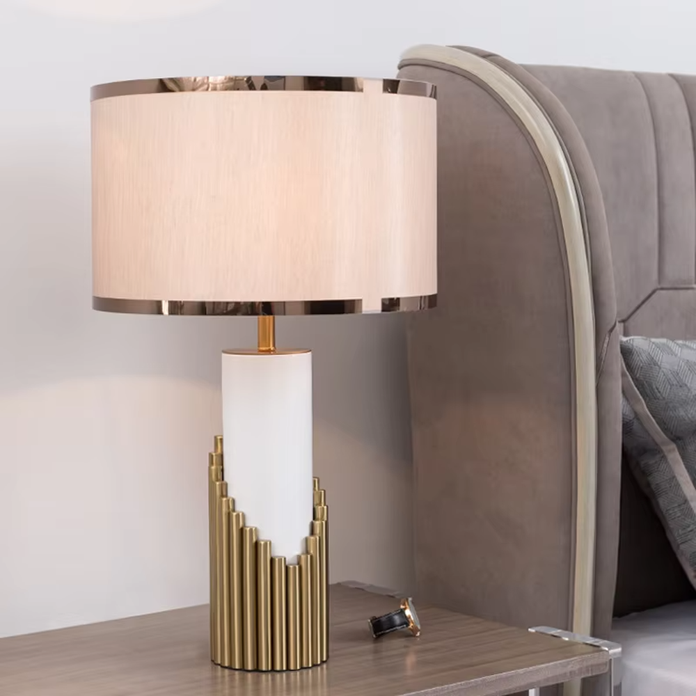 This is a light luxury-style gold and white metal fabric table lamp, with a golden staggered metal column base, paired with a white cylinder and a beige fabric lampshade (golden edging). It features a minimalist light luxury design, with warm and soft lighting. It is used for local desktop lighting and decoration, creating a light luxury and warm atmosphere. Suitable for light luxury-style bedroom bedside tables, modern minimalist living room side tables, high-end hotel guest rooms and other places.